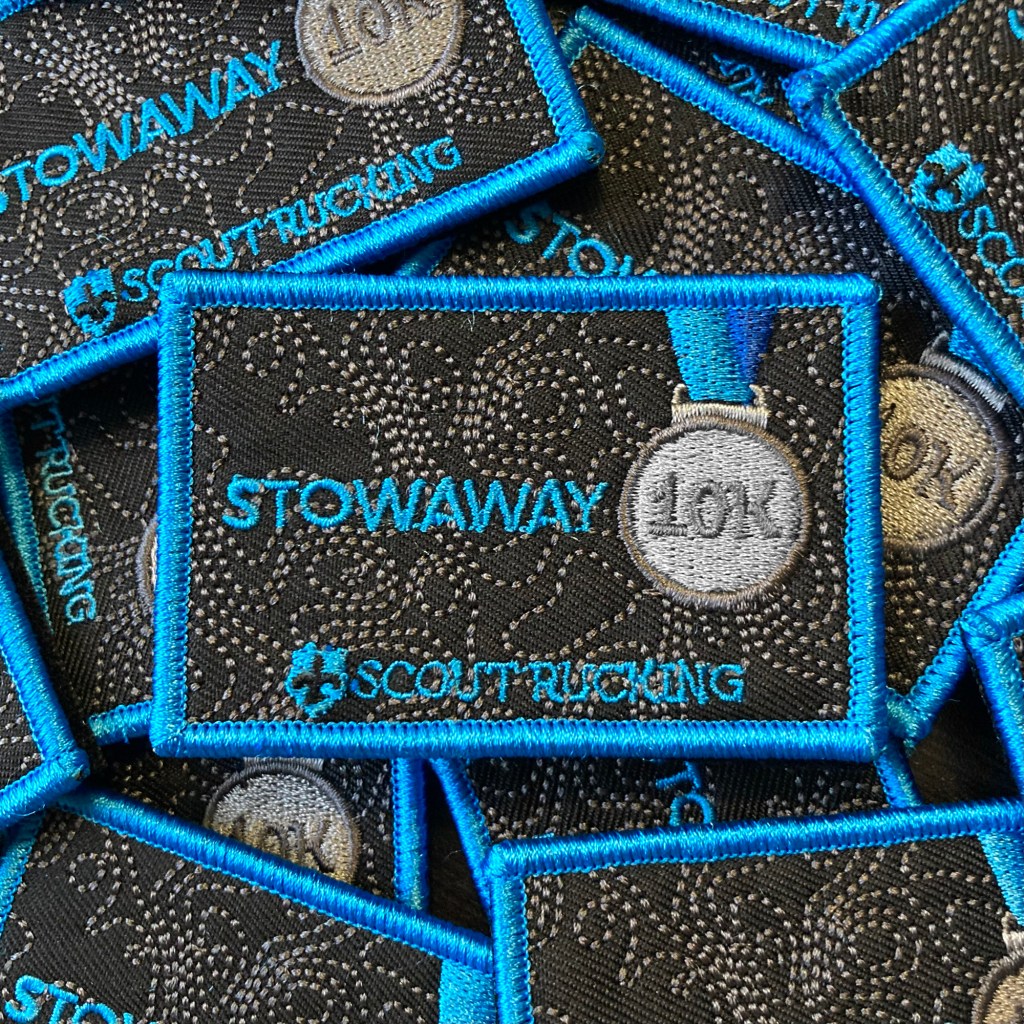 Pile of embroidered tactical patches with the Scout Rucking logo and the words, "Stowaway 10K."